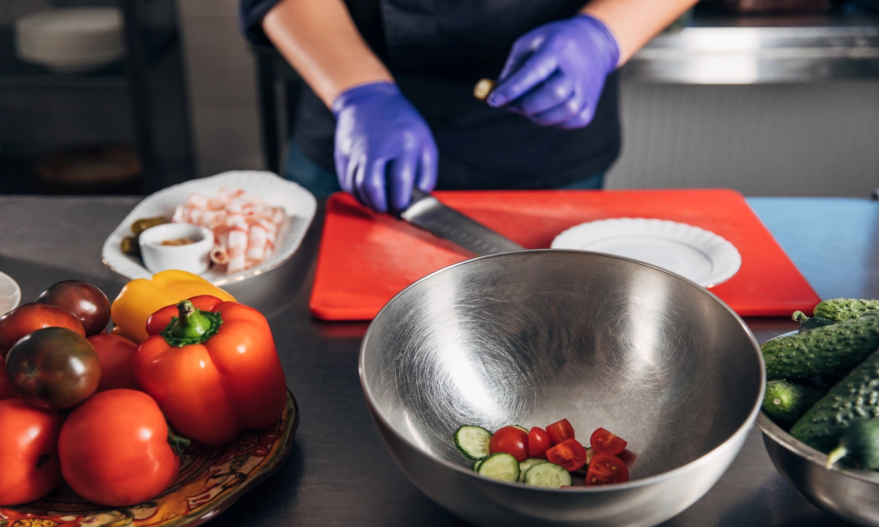 Food preparation scene showing fresh vegetables being cut safely on a sanitized surface.